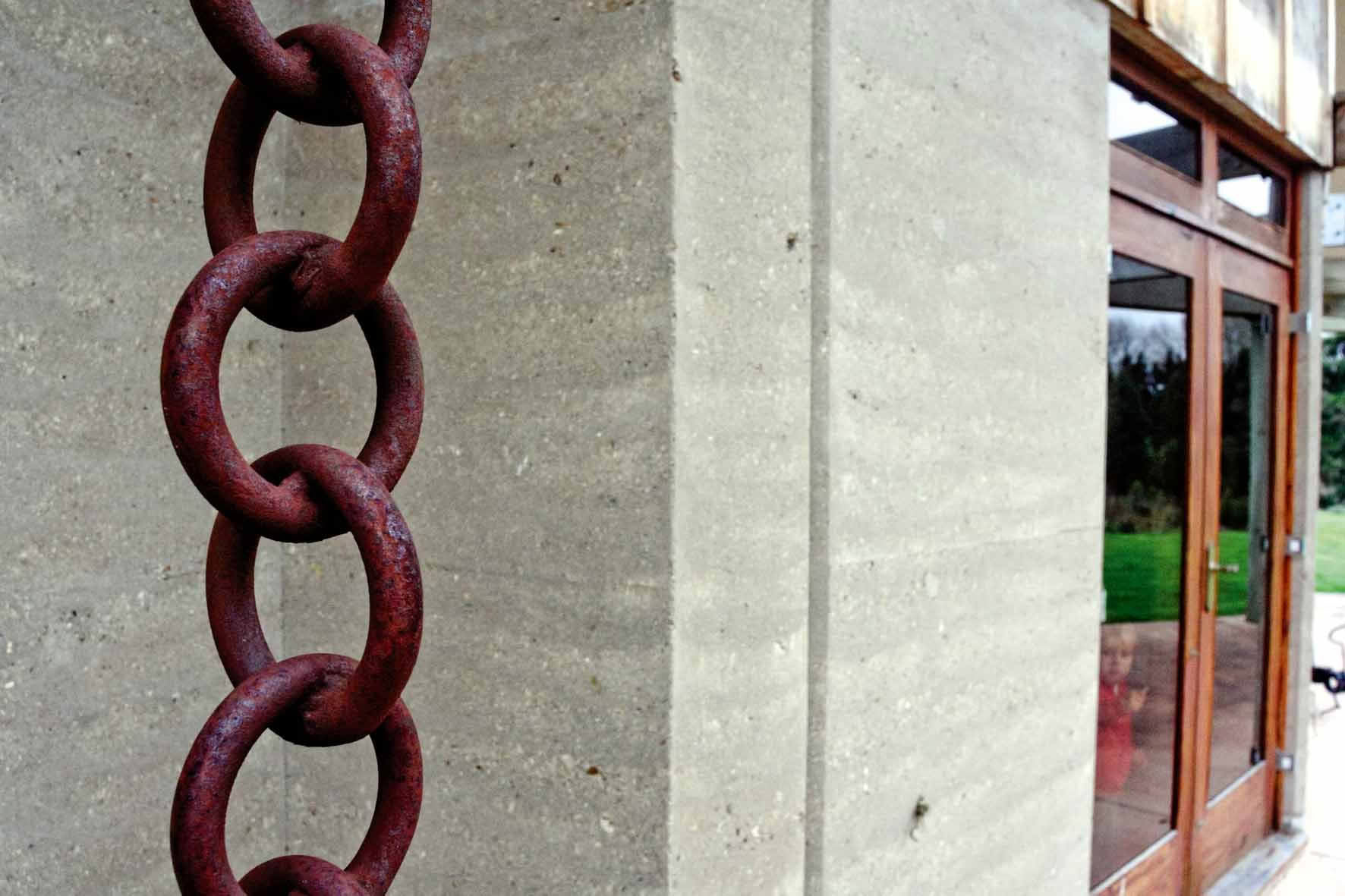 Rammed earth, with a chain 'downpipe'.