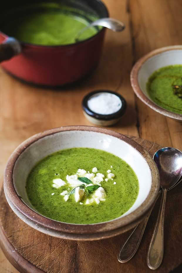 A bowl of potato leek soup sprinkled with feta and parsley. 