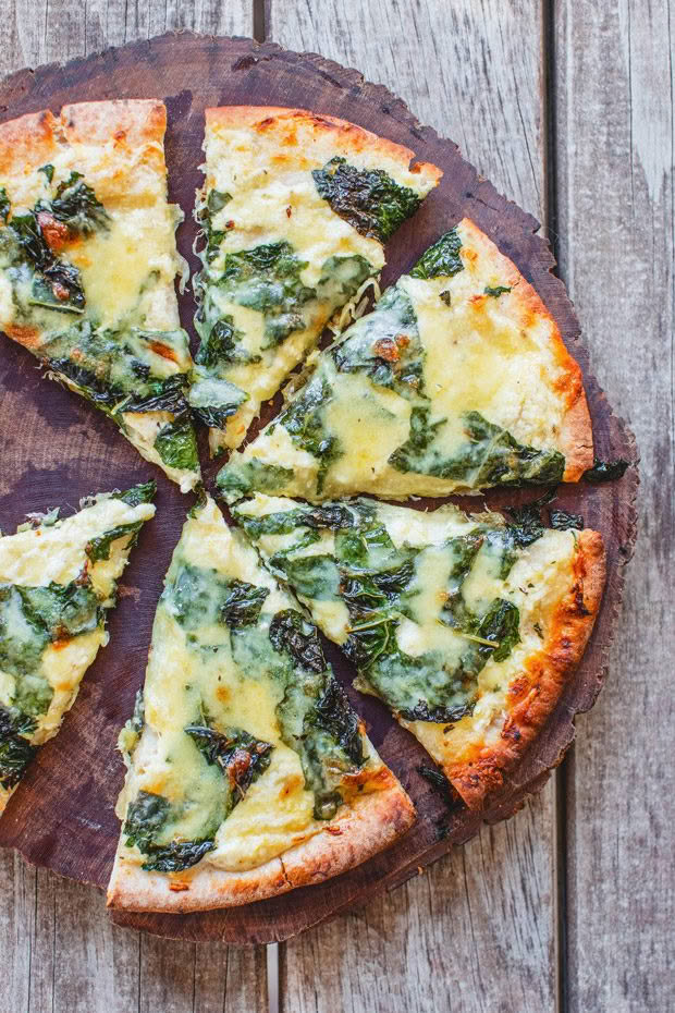 A cutting board with homemade cavolo nero (or kale) and lemon pizza. 