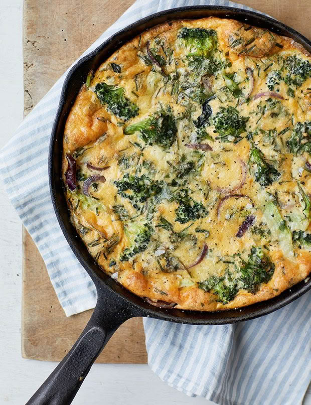 Frittati in a skillet with broccoli, onion and leftover vegetables.