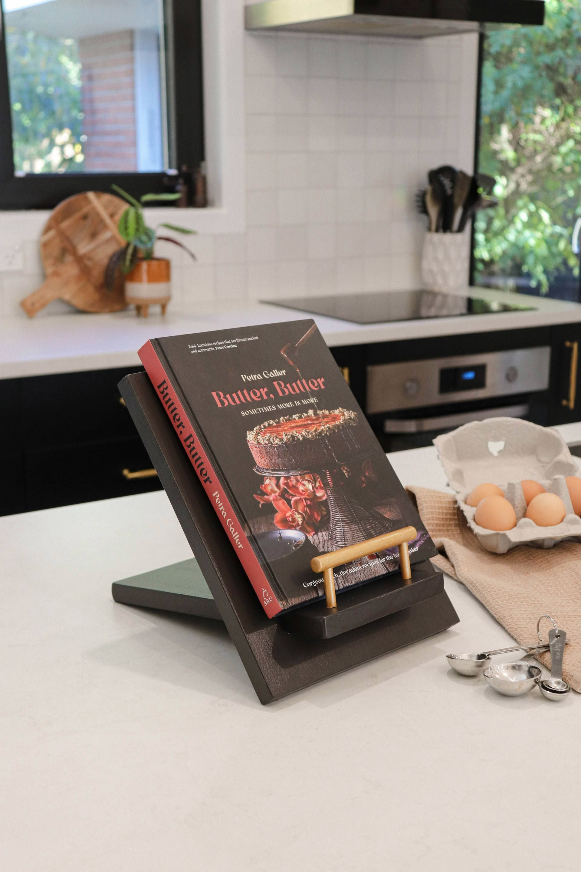 A book is sitting on top of a book stand on a kitchen counter.