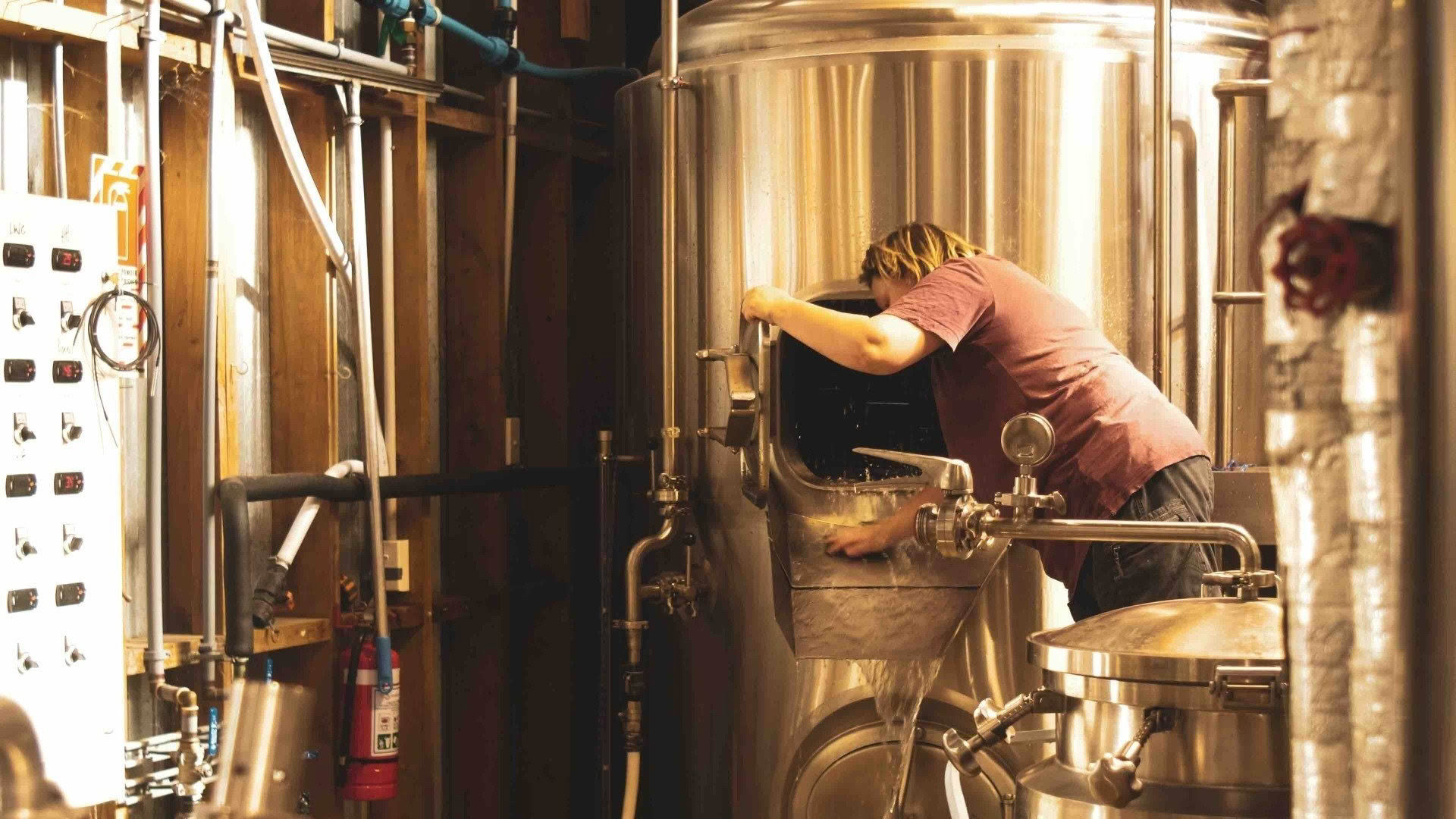 A man is working on a machine in a brewery.