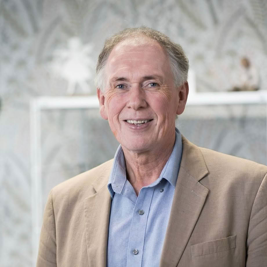 A man in a suit and blue shirt is smiling for the camera.