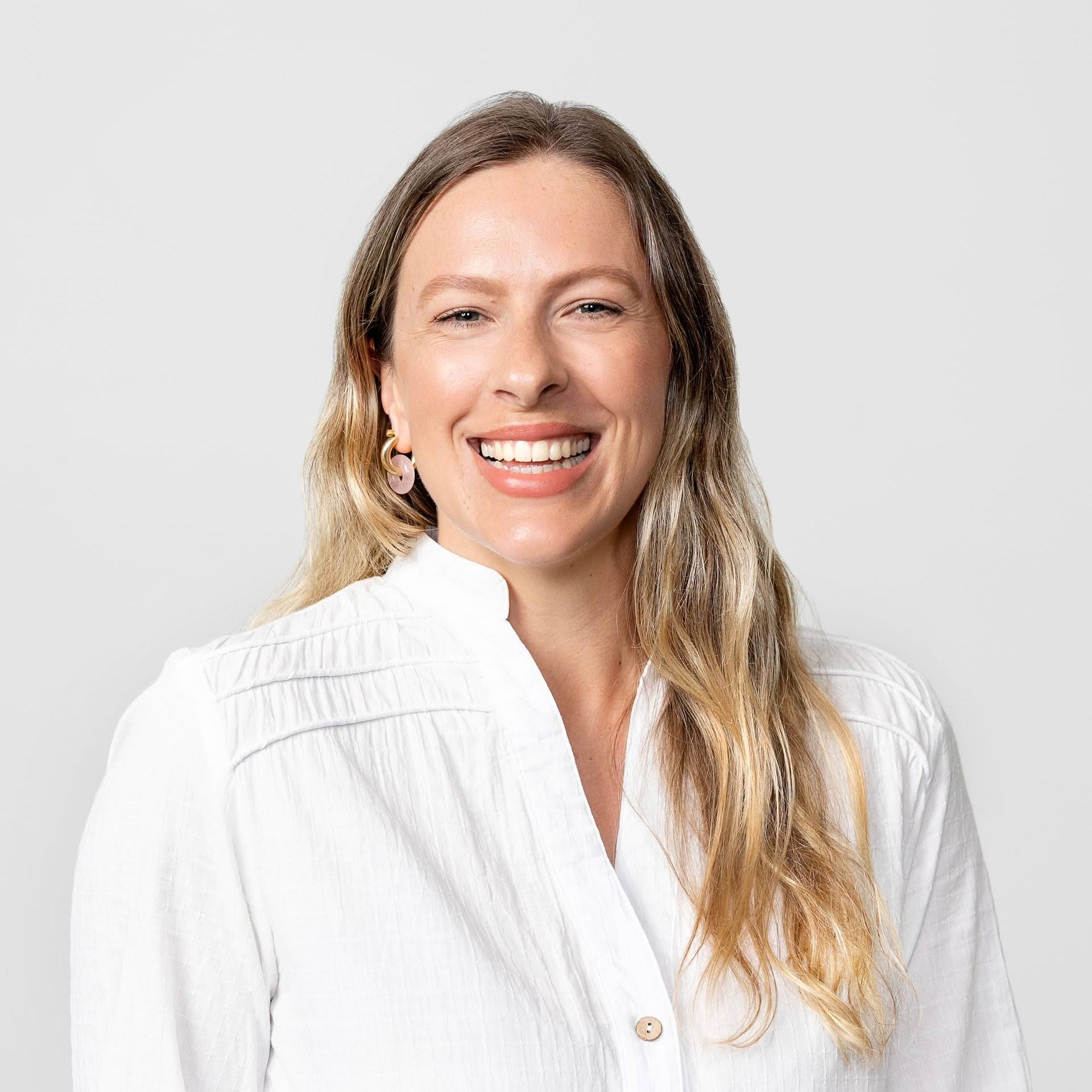 A woman in a white shirt is smiling for the camera.