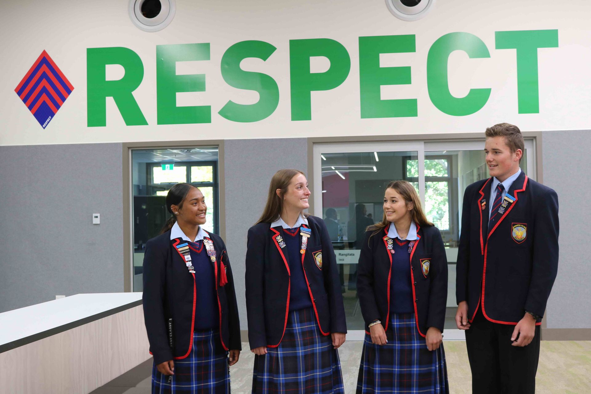 A group of students are standing in front of a sign that says respect.