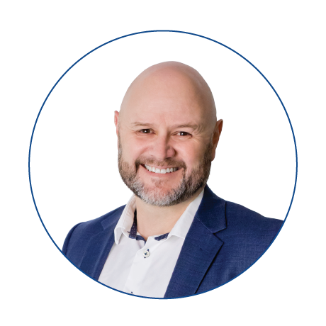 A bald man with a beard is wearing a blue suit and white shirt.