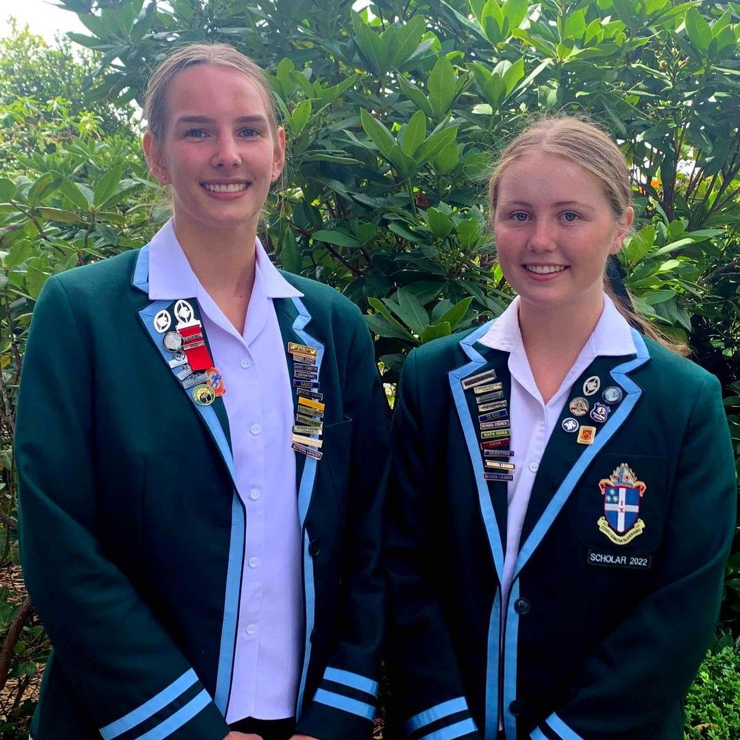 Two girls in school uniforms are standing next to each other