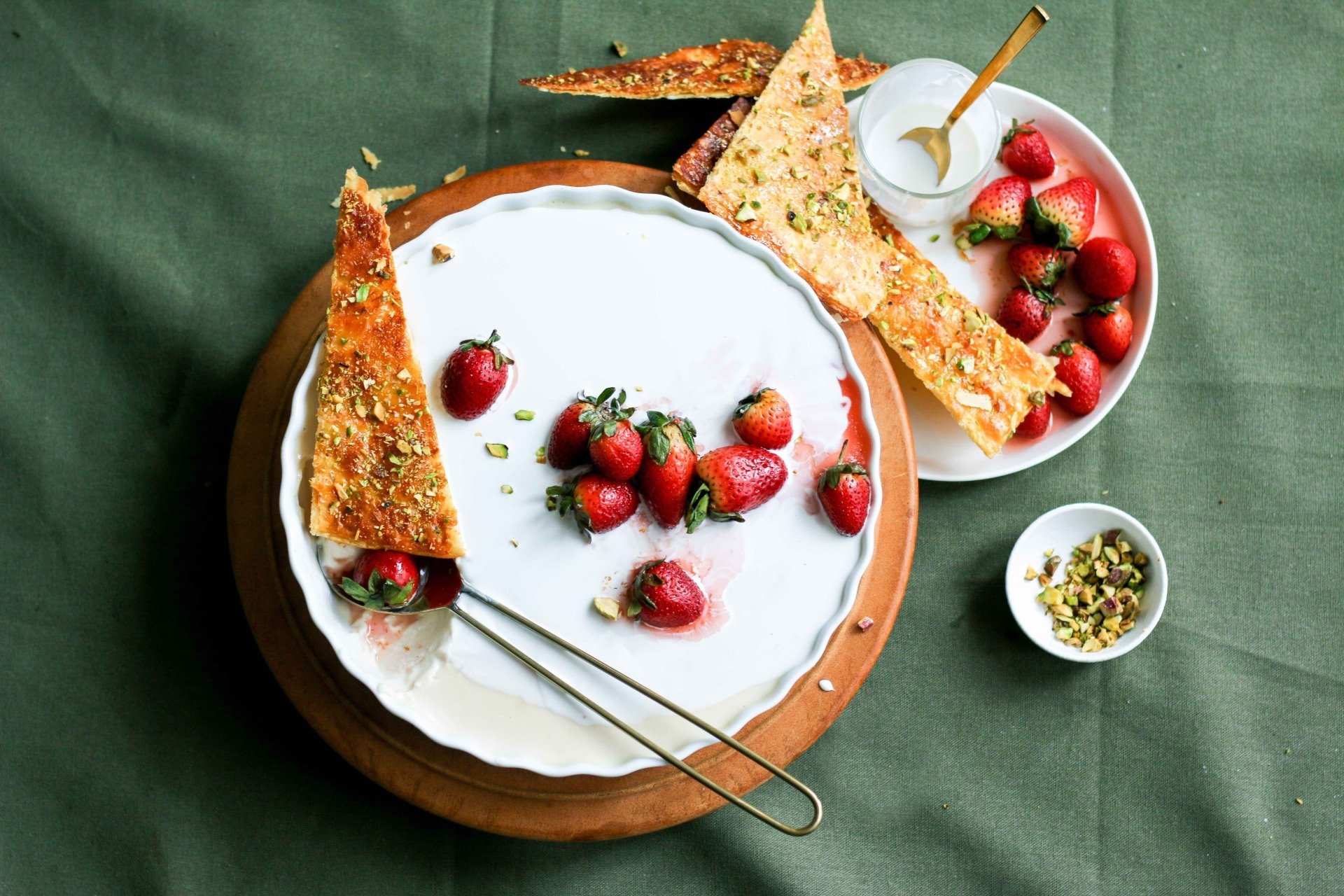 A white plate topped with strawberries and a spoon on a table.