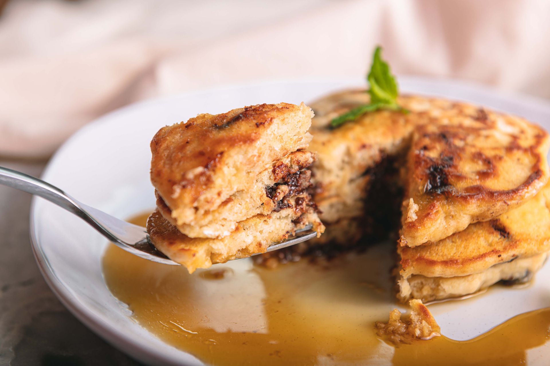 A close up of a plate of pancakes with syrup and a fork.