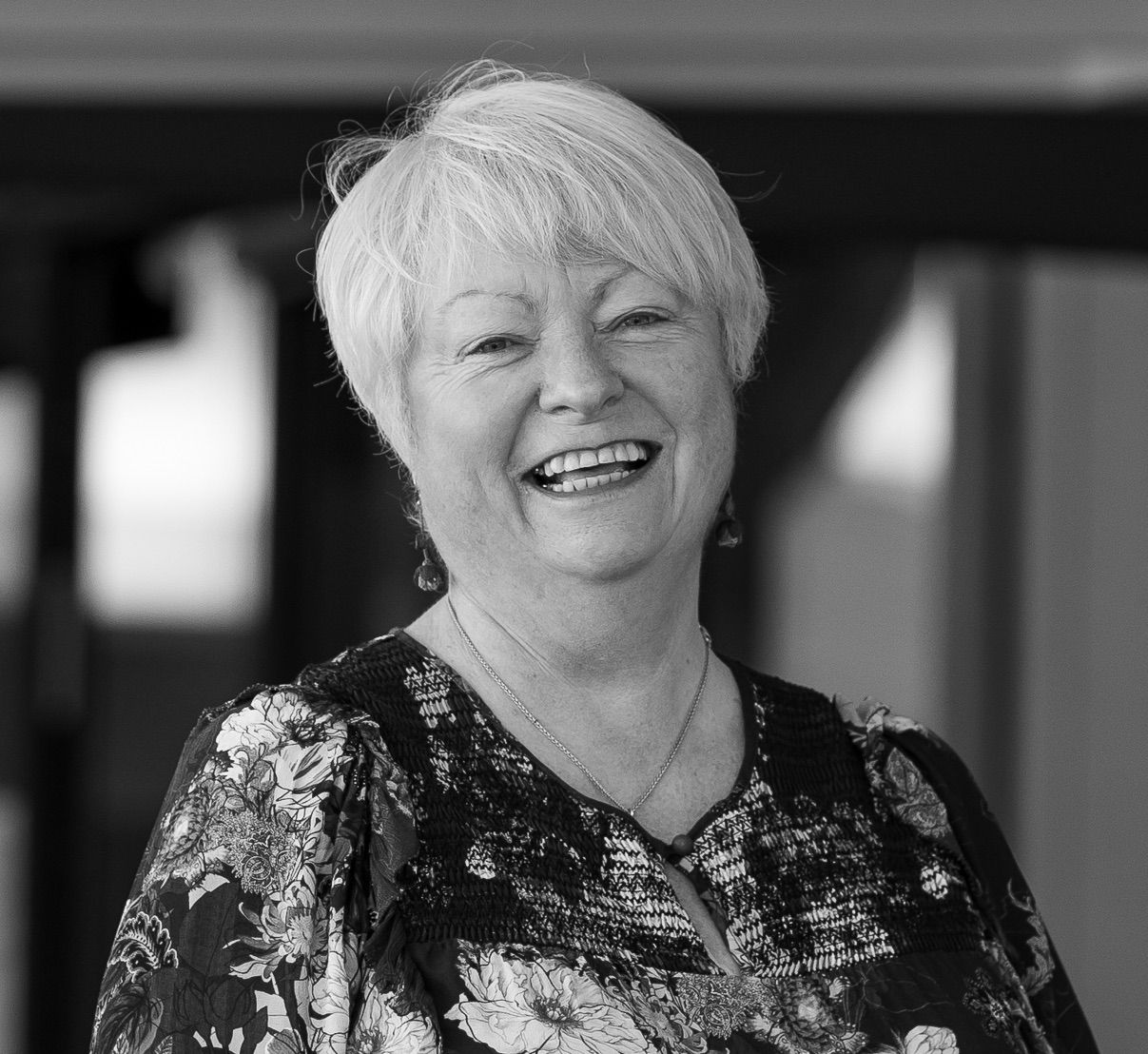 A woman is smiling in a black and white photo.