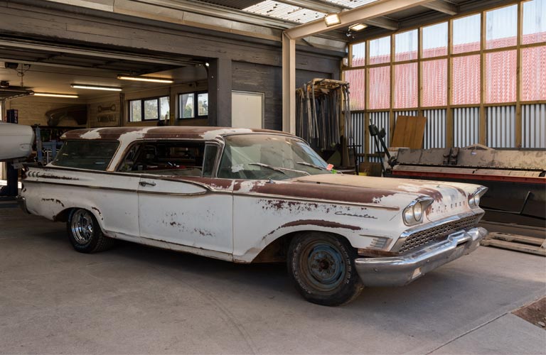 A white and brown car is parked in a garage.