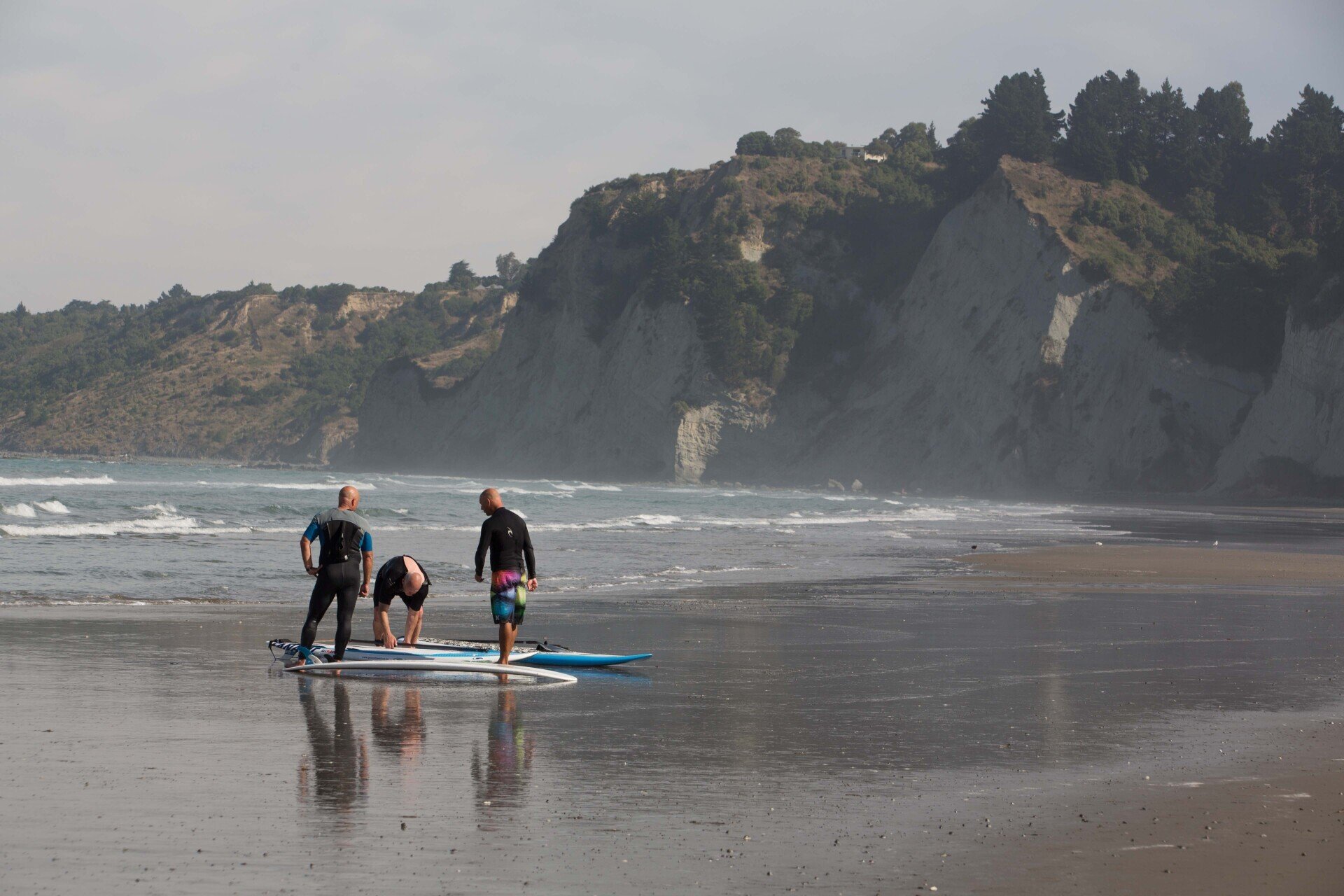 A group of people are standing on a beach with surfboards.