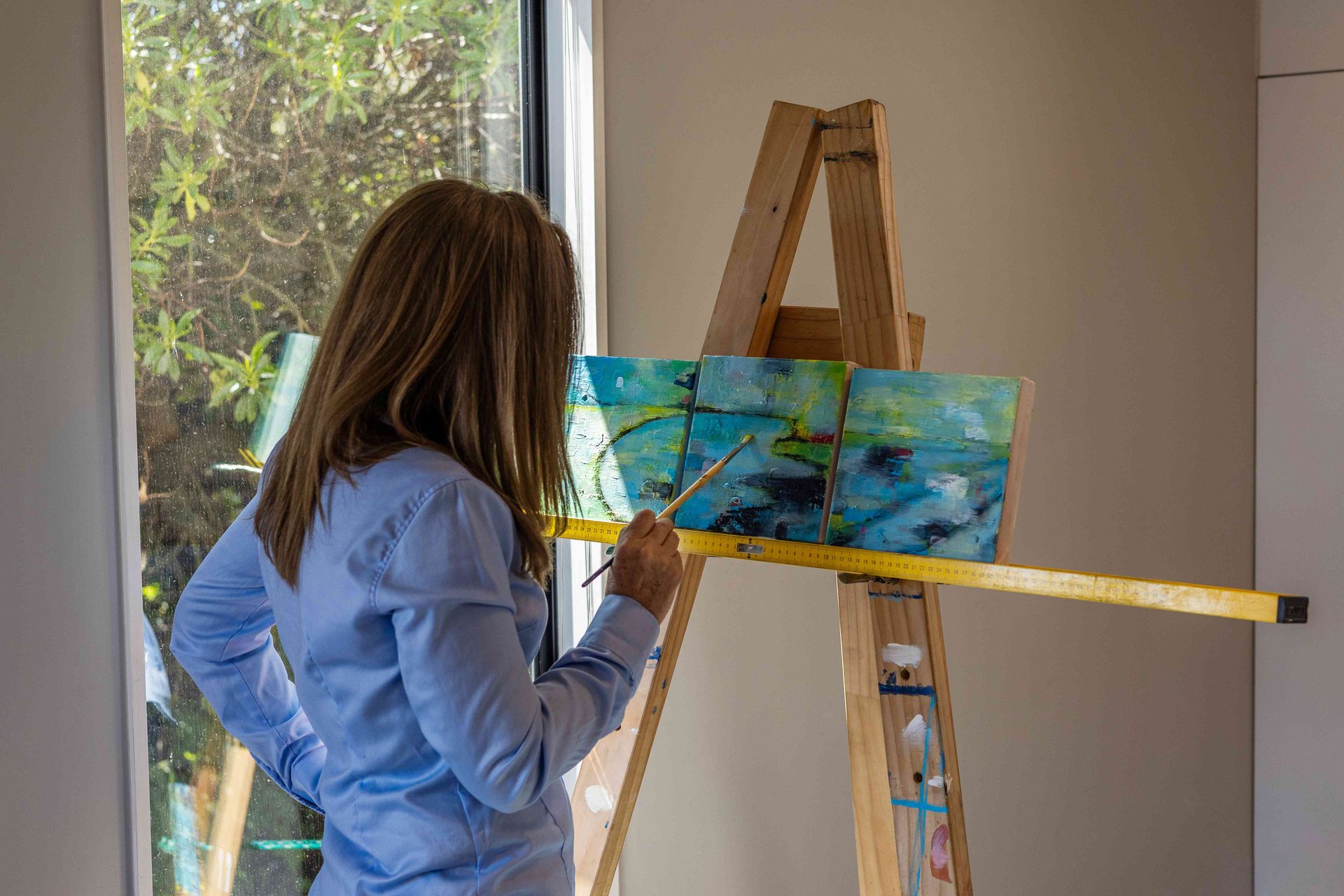 A woman is painting a picture on an easel.