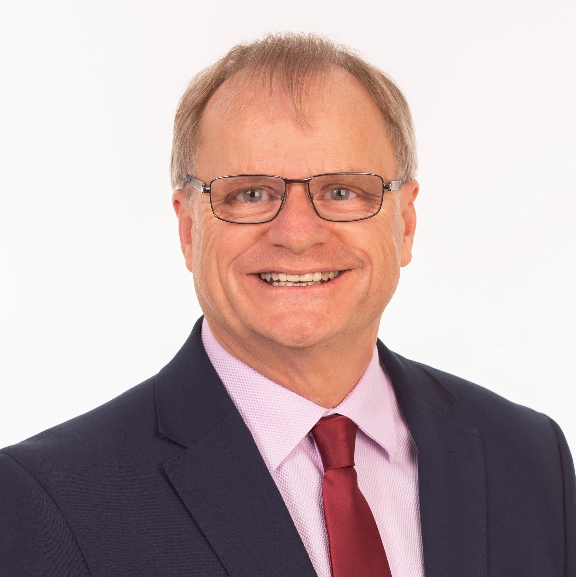 A man in a suit and tie is smiling for the camera.