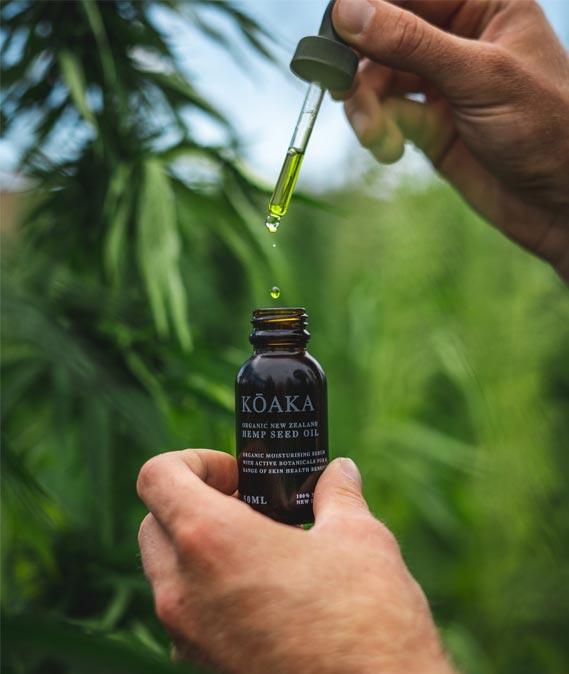 A person is holding a bottle of koaka oil with a dropper