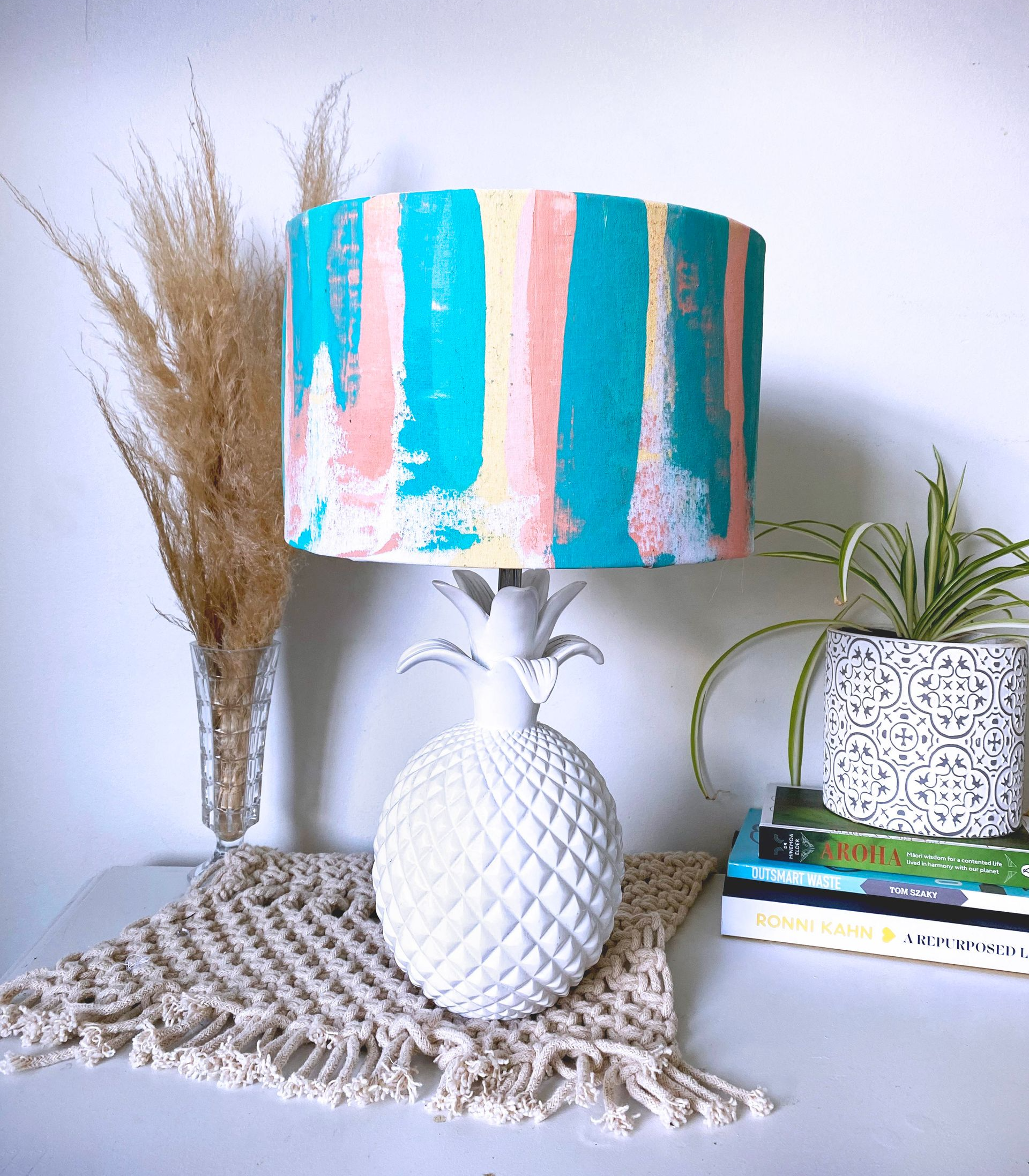 A white pineapple lamp with a blue and pink striped shade