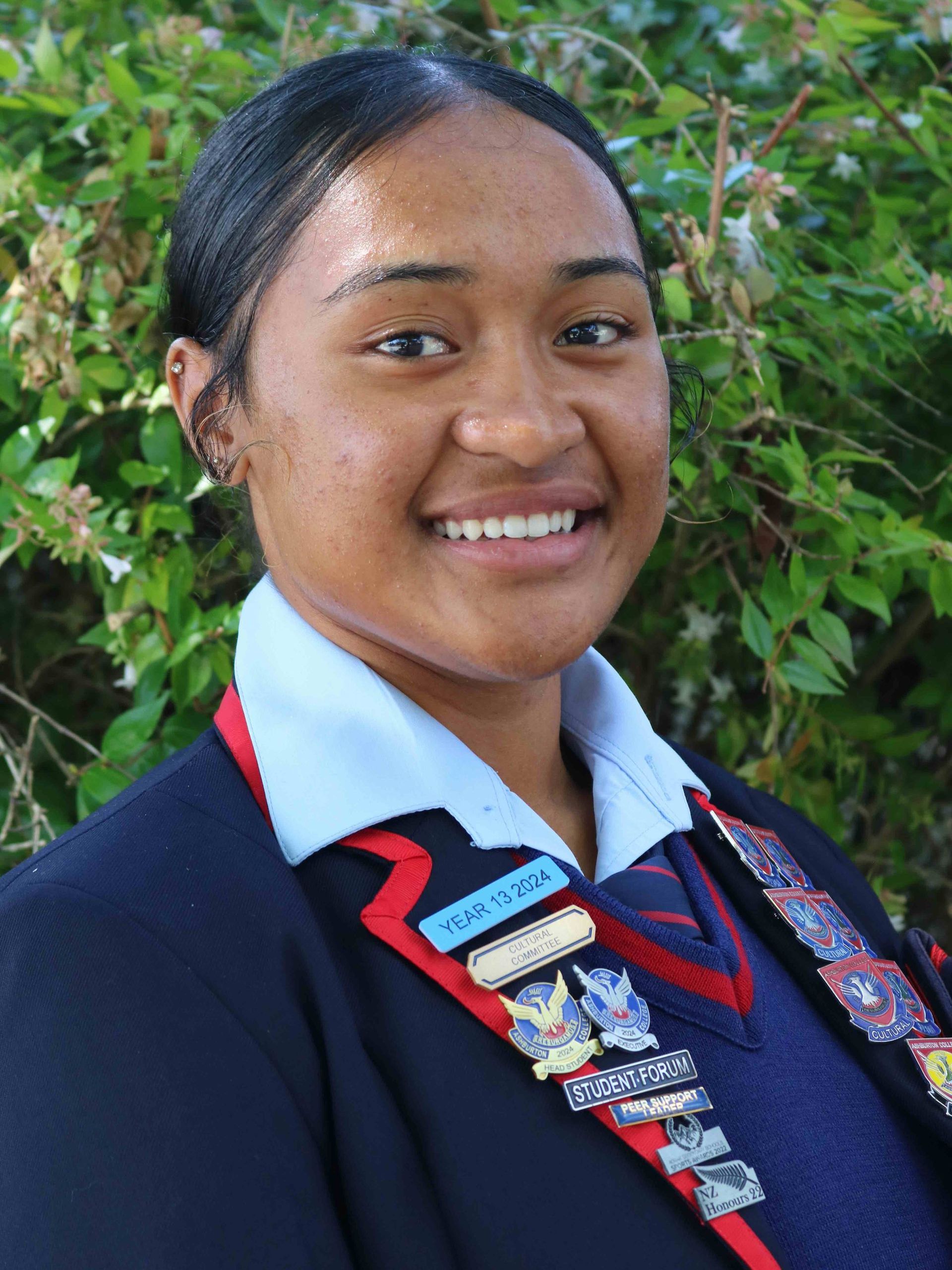 A young woman in a school uniform is smiling for the camera.