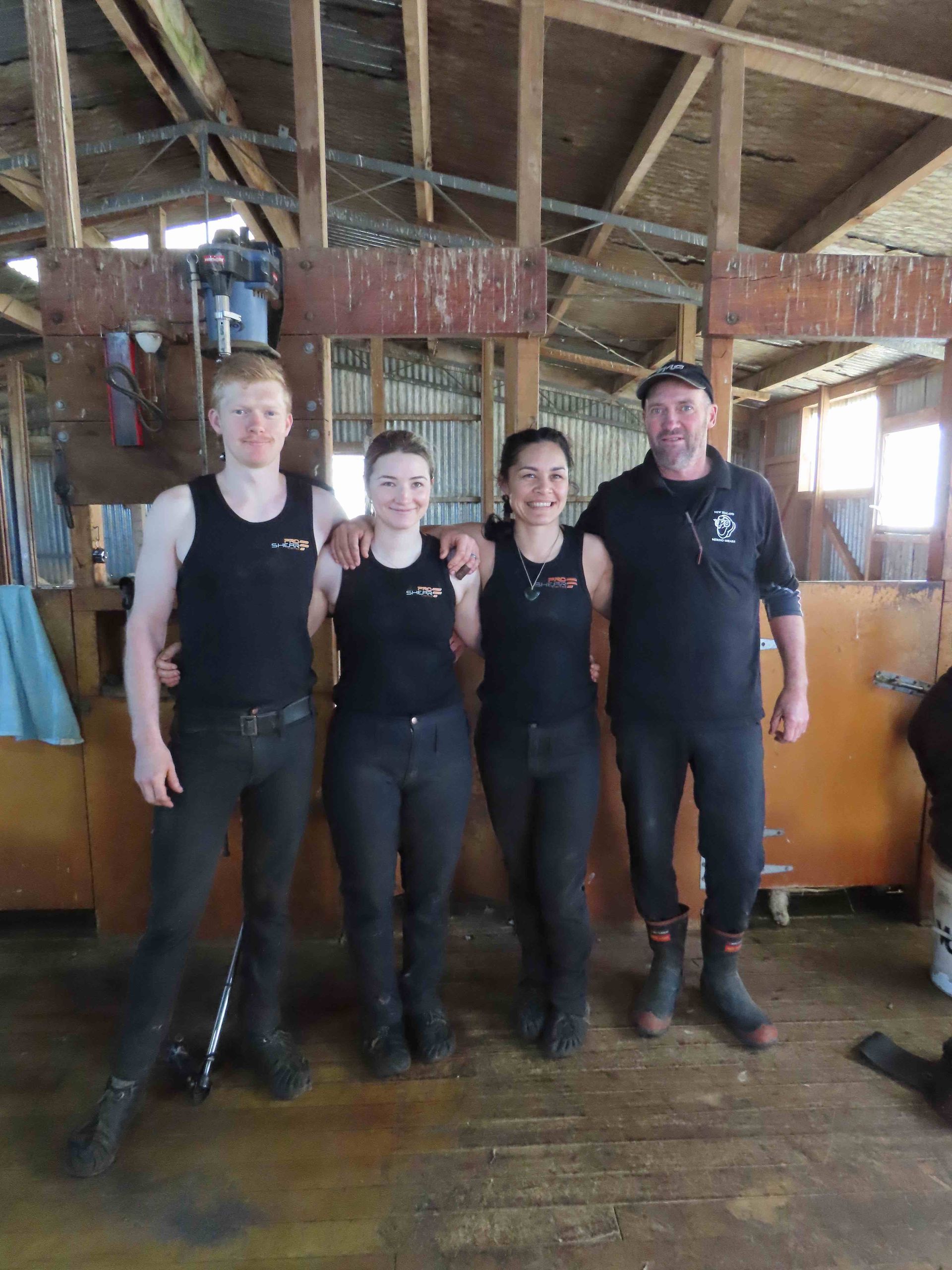 A group of people are posing for a picture in a barn.