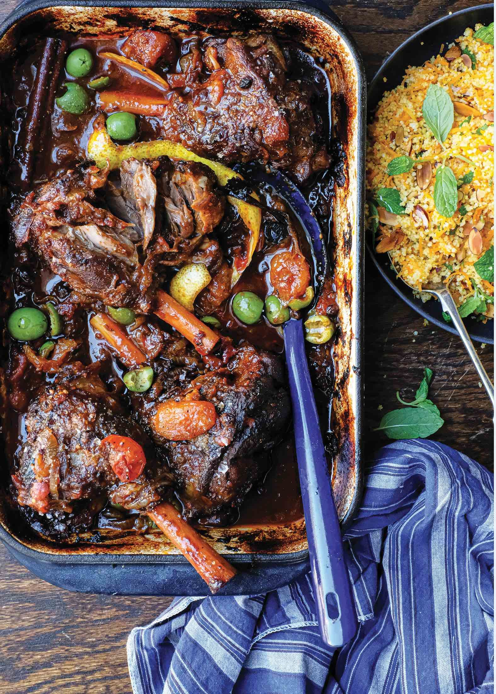 A casserole dish filled with meat and vegetables next to a bowl of rice.